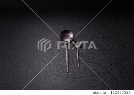 Cutlery fork, knife and spoon on a dark textured concrete background Cutlery fork, knife and spoon on a dark textured concrete background 112352582