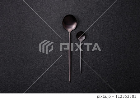Cutlery fork, knife and spoon on a dark textured concrete background 112352583