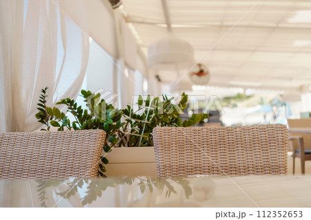 Wicker furniture tables in the open air are waiting for visitors. The interior of the restaurant in the open air. Empty tables of street cafe. 112352653