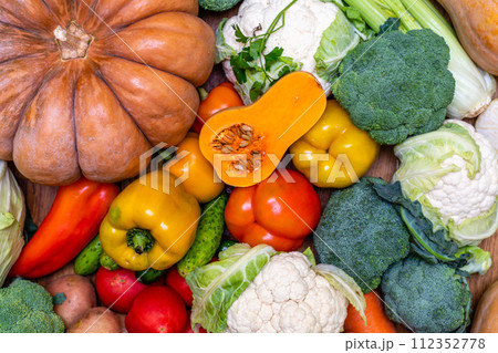 Various vegetables are laid out on a wooden table. Large assortment of vegetables food. pumpkin cabbage broccoli pepper tomatoes carrots and others 112352778