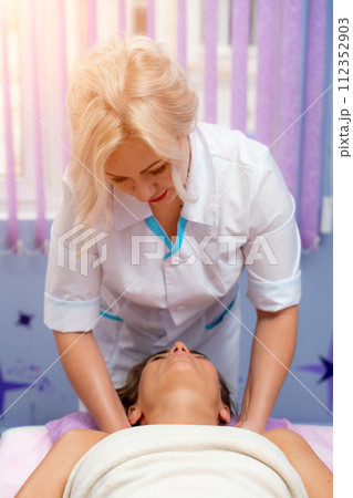Masseur woman massages her shoulders. Woman getting a massage at the spa 112352903