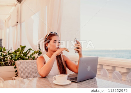 Woman coffee cafe macbook. Woman sitting at a coffee shop with mobile phone drinking coffee and looking away. Caucasian female relaxing at a cafe. 112352973