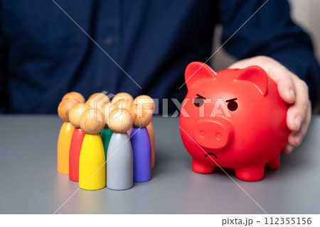 A businessman holds a red piggy bank next to a group of people figures. Lack of budget funds. Poor deposit conditions. Problems with pensions and savings systems. A businessman holds a red piggy bank next to a group of people figures. Lack of budget funds. Poor deposit conditions. Problems with pensions and savings systems. 112355156