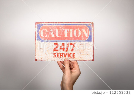 24 HRS 7 DAYS service. Metal warning sign in a woman's hand on a white background 112355332