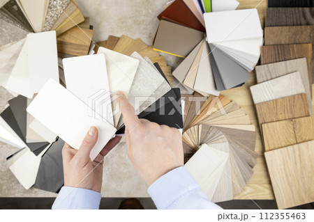 A woman looks at samples of furniture panels for furniture design. The concept of home furnishing. A woman looks at samples of furniture panels for furniture design. The concept of home furnishing. 112355463