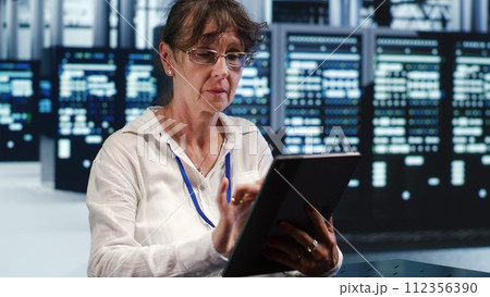 Competent tech support woman working in high tech space housing GPU dedicated servers that can process AI tasks with high efficiency, troubleshooting rigs used for machine learning showing hiccups 112356390