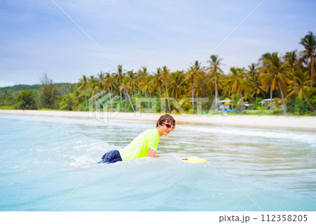 Surfer on tropical beach. Boy surfing. 112358205