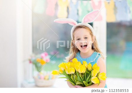 Little girl in bunny ears on Easter egg hunt 112358553