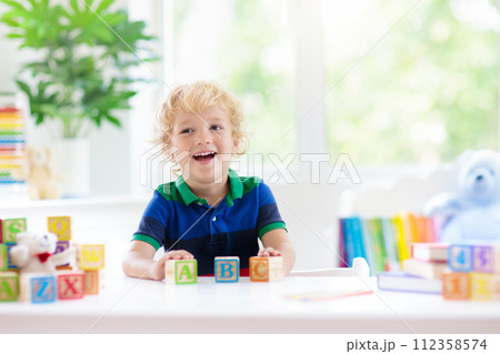 Child learning letters. Kid with wooden abc blocks 112358574