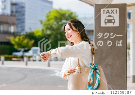 タクシー乗り場でタクシーを待つビジネスウーマン(腕時計) タクシー乗り場でタクシーを待つビジネスウーマン(腕時計) 112359387