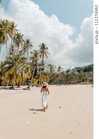 A woman in a hat enjoys the summer sun on a beautiful tropical beach 112359862