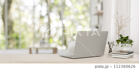 A back view image of a laptop on a wooden desk in a minimalist bright living room. 112360626