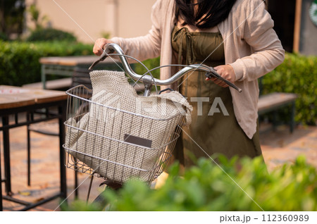 A cropped shot of a woman pushing her bicycle on the street in the city. 112360989