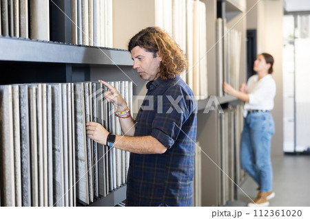In construction mall,man checks drawing of decorative slabs for suspended ceiling 112361020