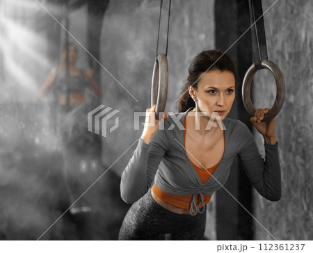 Woman performs exercises using simulator machine with rings in gym 112361237
