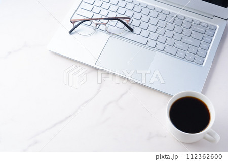 コーヒーを飲みながらノートパソコンでデスクワーク中のイメージ	 112362600