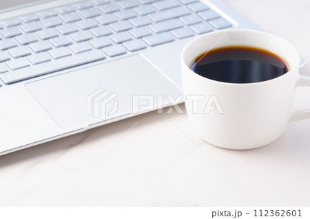 コーヒーを飲みながらノートパソコンでデスクワーク中のイメージ	 112362601