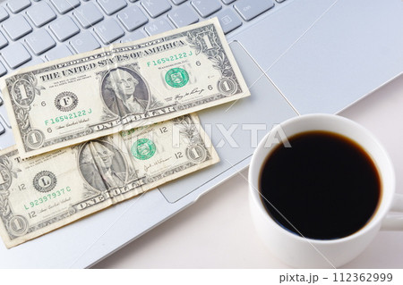 アメリカ合衆国ドル（US＄）の1ドル紙幣とコーヒーが入ったコーヒーカップ 112362999