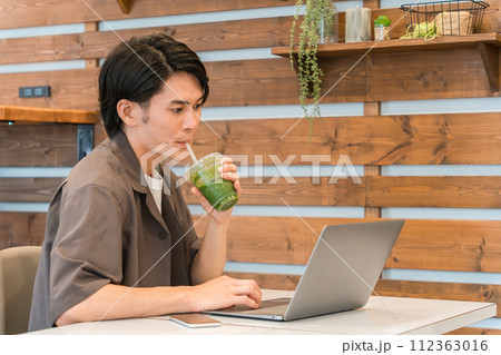 パソコン・仕事をしながらグリーンスムージー・青汁・野菜ジュースを飲んで断食・ダイエットする男性 パソコン・仕事をしながらグリーンスムージー・青汁・野菜ジュースを飲んで断食・ダイエットする男性 112363016