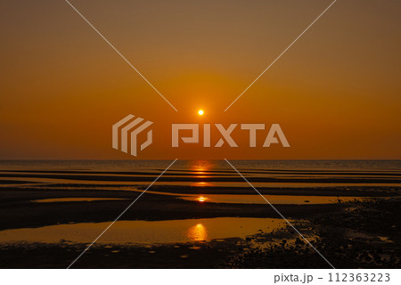 水平線に沈む真玉海岸の夕陽 112363223