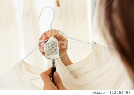 衣服の洗濯表示タグをルーペで拡大する女性. 112363498