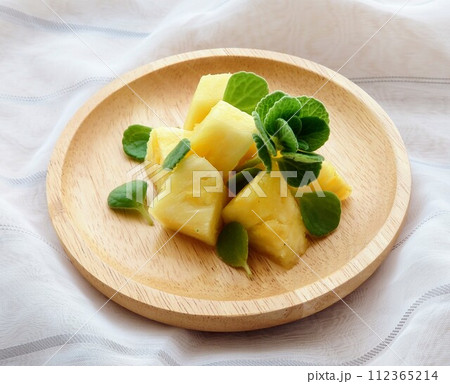 木のお皿に盛り付けられたパイナップルとアロマティカス 112365214