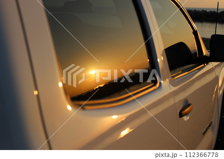 車のガラスに映り込む日本海の夕陽 112366778