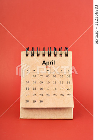 April 2024 white mini desk calendar on red background. April 2024 white mini desk calendar on red background. 112366883