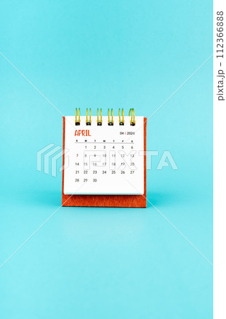 April 2024 white desk calendar on blue background. 112366888