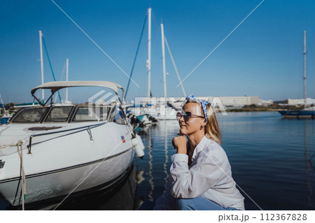 Woman in white shirt in marina , surrounded by several other boats. The marina is filled with boats of various sizes, creating a lively and picturesque atmosphere. Woman in white shirt in marina , surrounded by several other boats. The marina is filled with boats of various sizes, creating a lively and picturesque atmosphere. 112367828