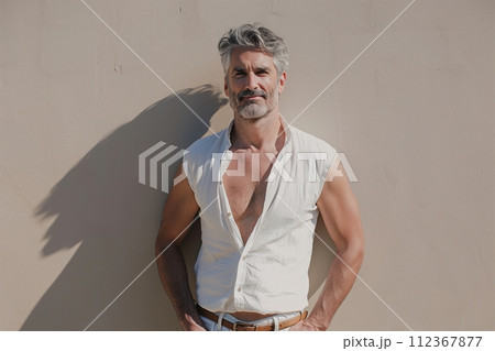 A man with a beard and mustache stands in front of a wall 112367877
