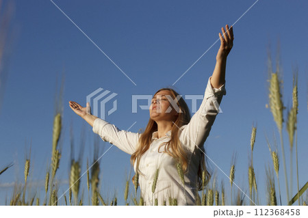 Woman in field with raised hands Woman in field with raised hands 112368458