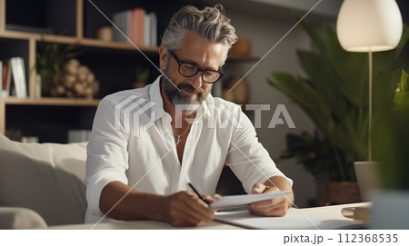AI-generated content. A stylish adult man with a beard is sitting at a table in cozy room hold a paper and pen 112368535