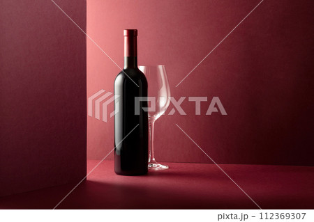 Bottle and glass of red wine on a red background. 112369307