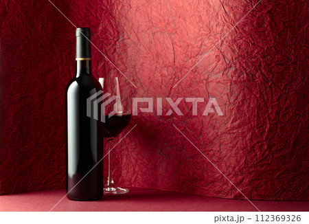 Bottle and glass of red wine on a red background. Bottle and glass of red wine on a red background. 112369326