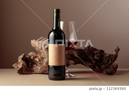Bottle and glass of red wine with old weathered snag. 112369368