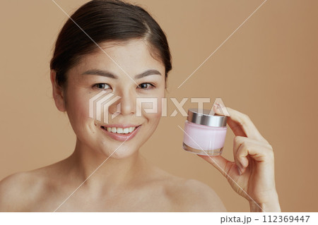 Portrait of young asian female with facial cream jar Portrait of young asian female with facial cream jar 112369447