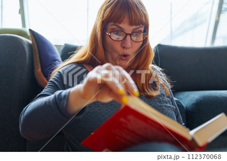 Portrait red-haired woman reading novel book 112370068