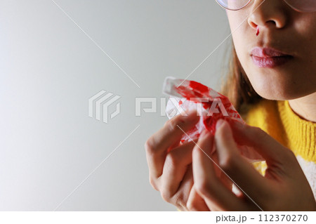 鼻血をティッシュ拭う女性 112370270
