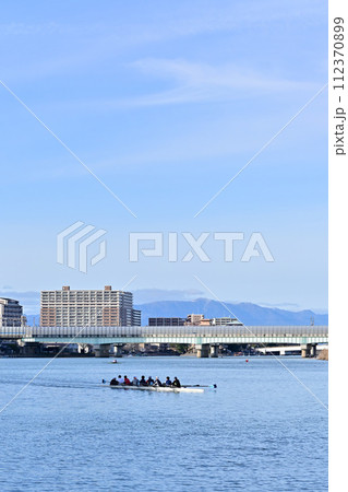 河川敷から見た街の眺めとボート部の練習 河川敷から見た街の眺めとボート部の練習 112370899