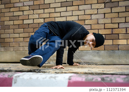 Man hip hop dancer or bboy freezes dancing on footpath during sunny day Man hip hop dancer or bboy freezes dancing on footpath during sunny day 112371394