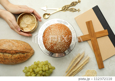 Bread, hands, grapes, wooden cross on book and spikelets on light background, top view Bread, hands, grapes, wooden cross on book and spikelets on light background, top view 112372110