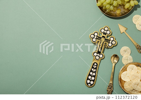 Liturgical bread, cross and grapes on green background, space for text 112372120