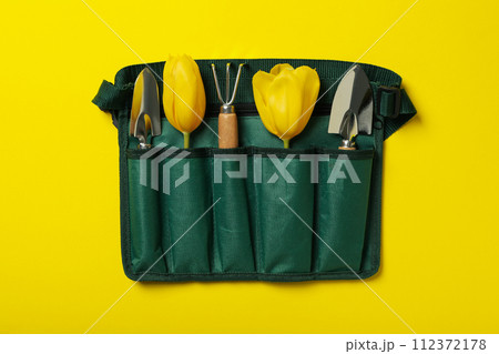 Garden tools and tulips in case on yellow background, top view 112372178