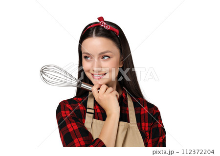 Housewife girl with kitchen utensils in her hands, on a gray background. 112372204