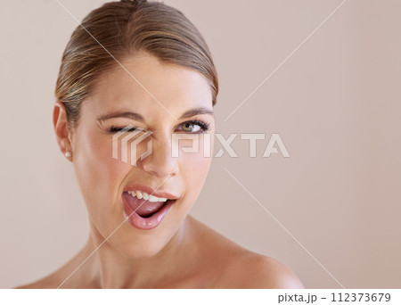 Portrait, wink and skincare of woman in makeup at spa facial treatment to shine. Face, beauty and model in cosmetics for glow, health or wellness isolated on a brown studio background mockup space Portrait, wink and skincare of woman in makeup at spa facial treatment to shine. Face, beauty and model in cosmetics for glow, health or wellness isolated on a brown studio background mockup space 112373679