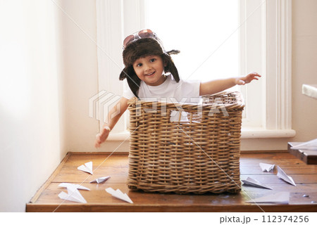 Flying, fun and child with paper plane, fantasy, and imagination playing in basket in home. Adventure, little pilot and playful boy in box with future dream, growth and development with airplane. 112374256
