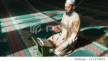 Islam, praying and man in mosque with Quran, mindfulness and gratitude in faith reading. Worship, religion and Muslim Imam in holy temple for praise with book, spiritual teaching and peace meditation Islam, praying and man in mosque with Quran, mindfulness and gratitude in faith reading. Worship, religion and Muslim Imam in holy temple for praise with book, spiritual teaching and peace meditation 112374852