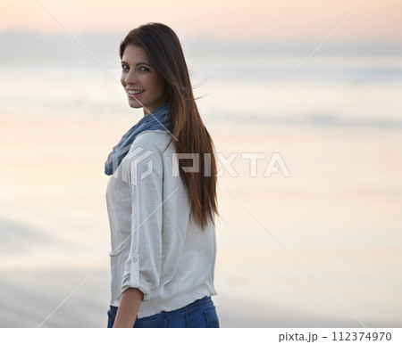 Woman, walking and smile in portrait at beach, sunset and vacation with nature to relax by ocean. Girl, person and outdoor by sea with walking for holiday, adventure and happy by coast in Australia 112374970