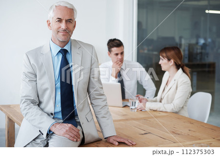 Portrait, smile and business man on table in boardroom of office for meeting, planning or management. Leadership, training or education with confident mature manager in workplace for employee growth Portrait, smile and business man on table in boardroom of office for meeting, planning or management. Leadership, training or education with confident mature manager in workplace for employee growth 112375303